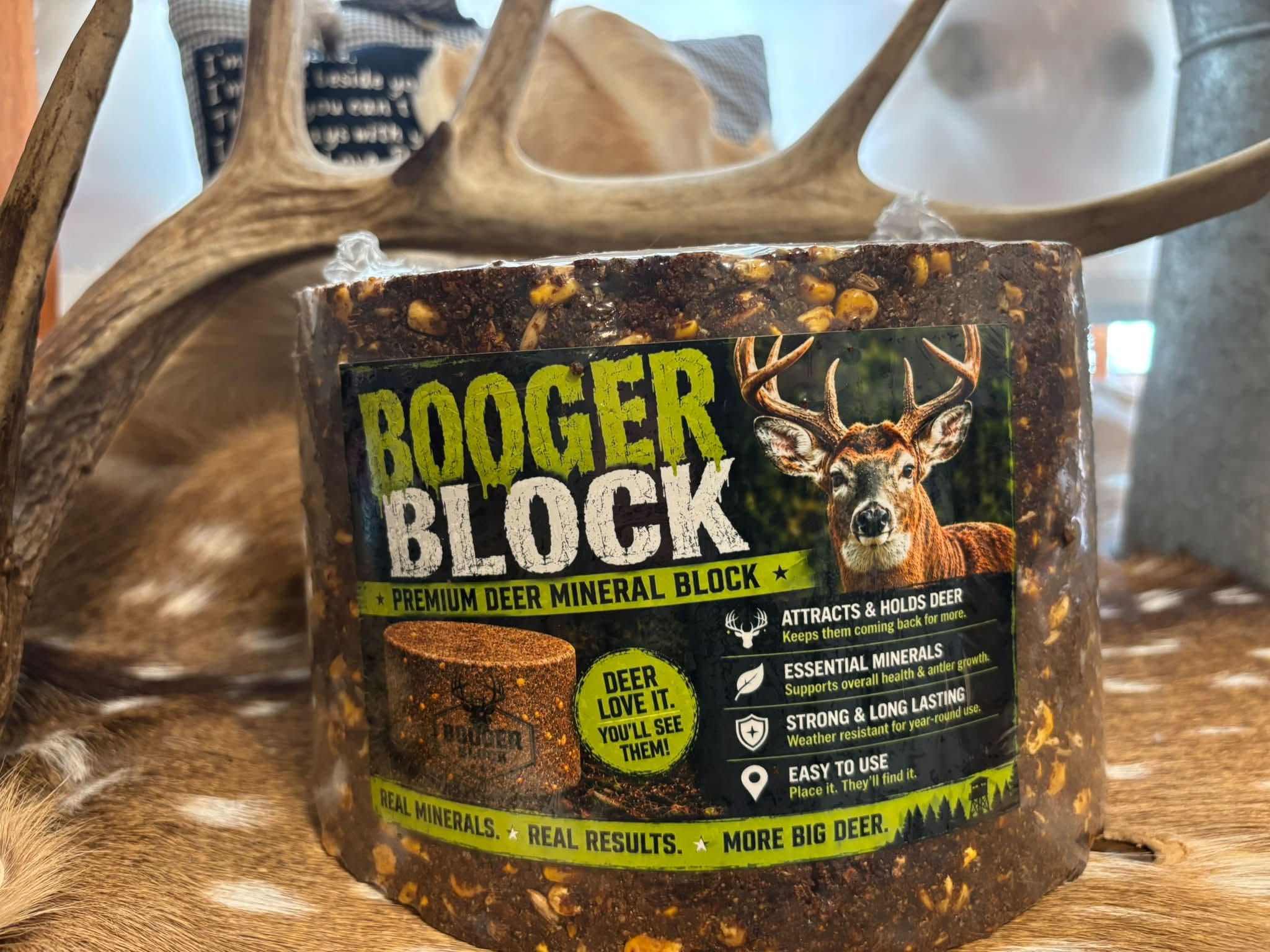 A Booger Block mineral deer block with its original label, displayed with antlers